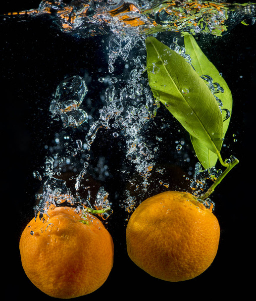Laranja e tangerinas na água com bolhas de ar
. - Foto, Imagem