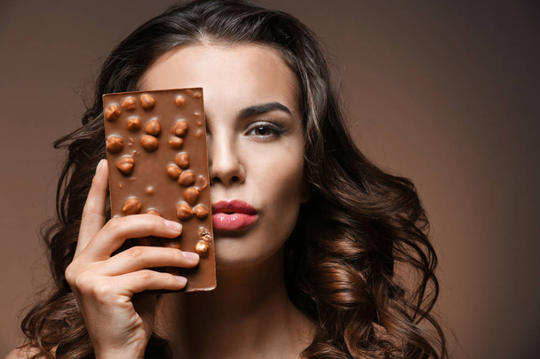 Beautiful girl with chocolate on brown background - Foto, Bild