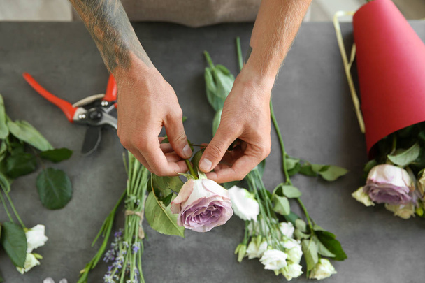 Male florist making bouquet at flower shop - Foto, afbeelding