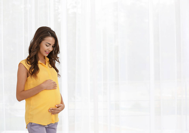 pregnant woman standing near window  - Foto, Bild
