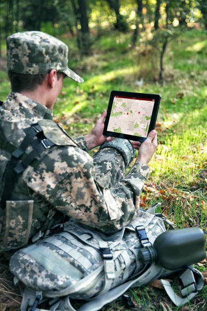 Soldier using map on tablet for orientation at forest - Фото, зображення