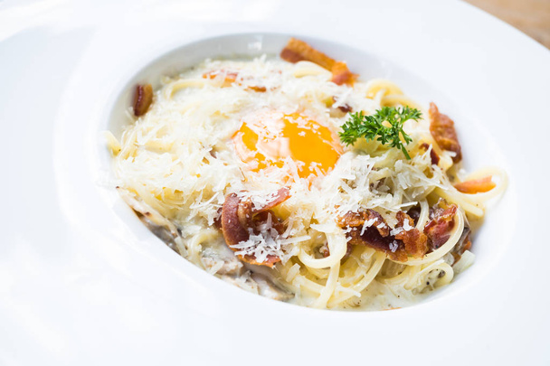 Spagetti carbonara nyers tojással a tetején - Fotó, kép