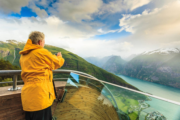 Tourist photographer with camera on Stegastein lookout, Norway - 写真・画像