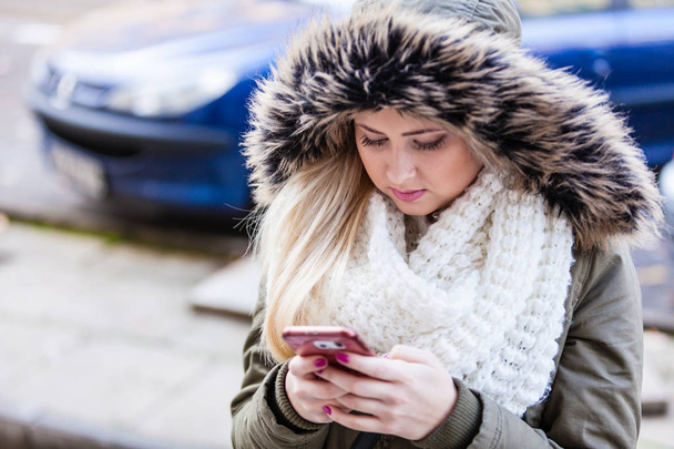 Woman using her smartphone outside on cold day - Фото, изображение