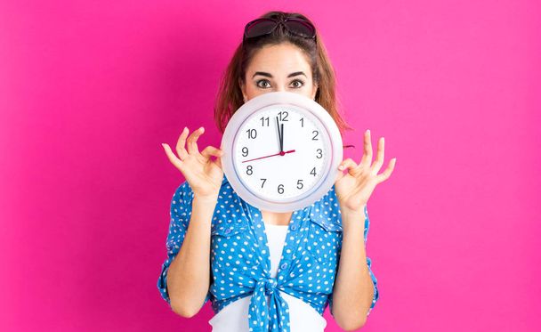 Woman holding clock showing nearly 12 - Фото, зображення