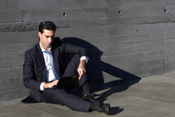 Бизнесмен с помощью ноутбука сидит на улице
 - Фото, изображение