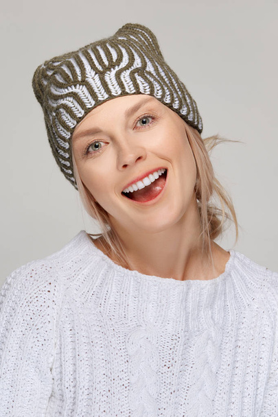Pretty fashion model in white sweater and knitted hat - Fotó, kép