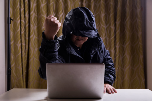 asiatische Hacker zeigen Faust, während sie Computernetzwerk hacken - Foto, Bild