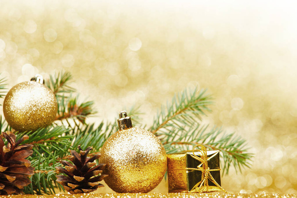 Christmas card with fir branch and decorations on golden gitter background - Foto, afbeelding