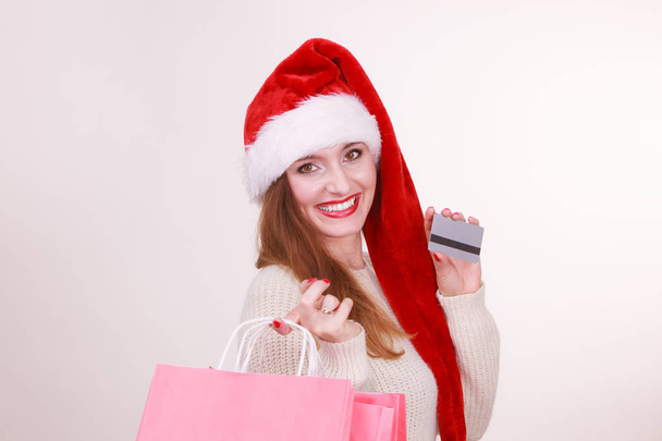 woman in Christmas hat holds credit card and shopping bags. - Fotoğraf, Görsel