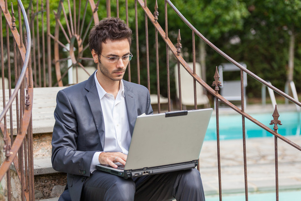 Young Businessman with Computer next to Swimming Pool - Fotografie, Obrázek