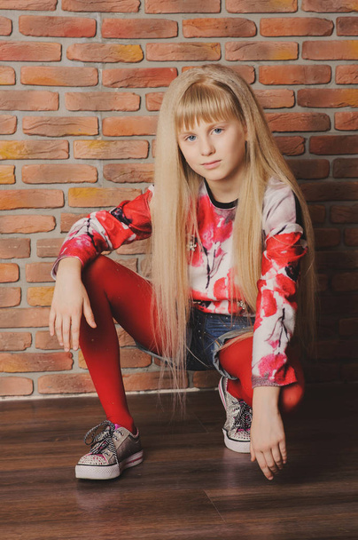 Beautiful modern girl in red near the brickwall. Youth style. - Photo, Image