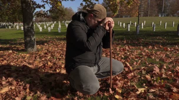 Depressed man with crutch in cemetery in autumn - Footage, Video