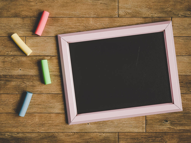 Chalkboard and colorful chalks over wooden table. 3D illustration - Foto, imagen