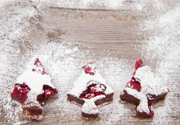 Noel ağacı ahşap bir zemin üzerine pudra şekeri ile kaplı ahududu kek şeklinde - Fotoğraf, Görsel