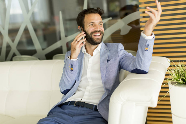 Homem de negócios moderno com telefone no escritório
 - Foto, Imagem