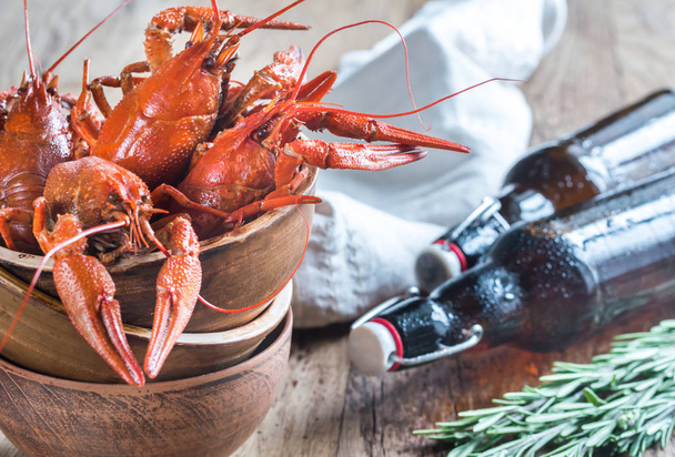 Bowl of boiled crayfish with bottles of beer - 写真・画像