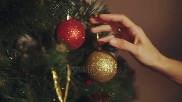 Las manos de la mujer juegan con la pelota en el árbol de Navidad de cerca
 - Metraje, vídeo