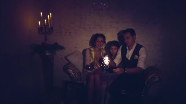 Happy family with daughter lighting sparklers in the dark at christmas eve - Footage, Video