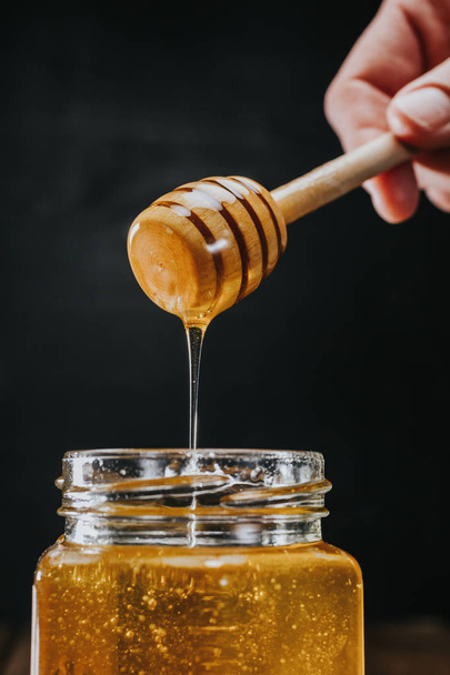 Personne trempant bâton de miel dans
 - Photo, image