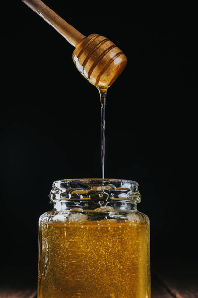 Person dipping honey stick in - Foto, Imagen