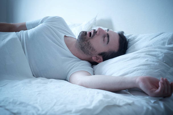 Man in zijn bed te slapen en snurken luid - Foto, afbeelding