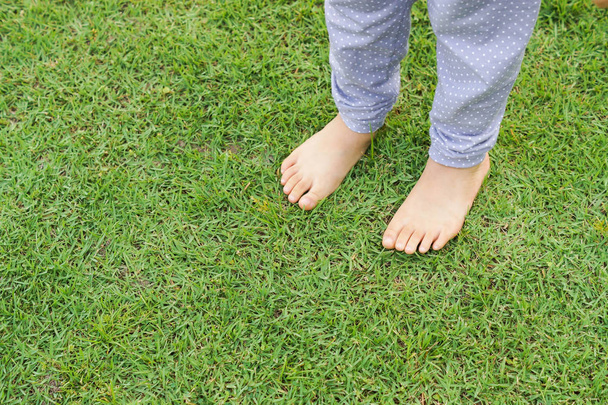 Pieds d'enfant debout sur l'herbe verte
 - Photo, image