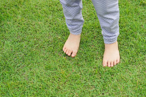 Дитячі ноги стоять на зеленій траві
 - Фото, зображення