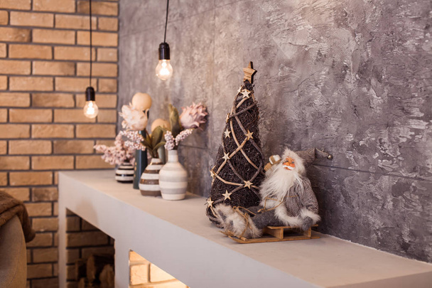 Small Santa Claus sitting at the upper part of contemporary fireplace. - Photo, Image