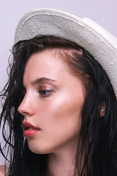 Fashion pretty young woman wearing a white straw hat in studio on a grey background - Foto, imagen