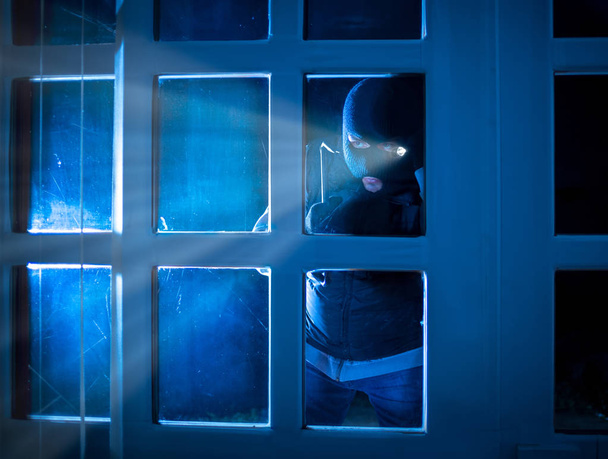 burglar standing in the dark outside and peering inside - Foto, afbeelding