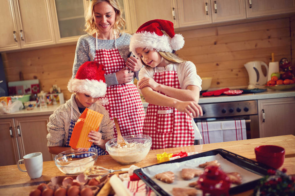 Family of children and mother baking cookies at home - Foto, afbeelding