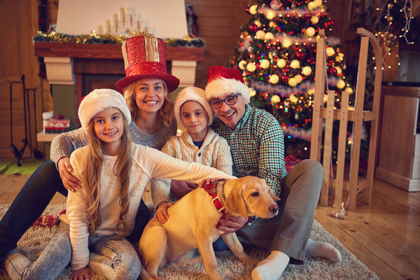family and dog sitting by xmas tree - Foto, imagen
