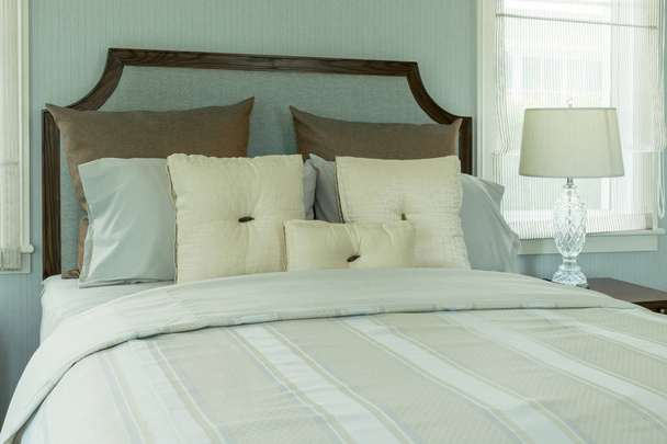 acogedor dormitorio interior con almohadas blancas y lámpara de lectura en la mesita de noche
 - Foto, Imagen