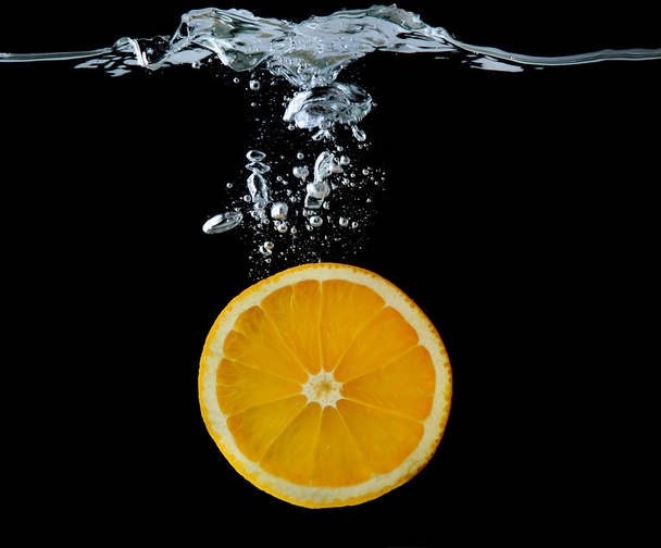 Slice of orange in the water on black background - Zdjęcie, obraz