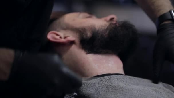 Peluquero afeita la barba del cliente en la barbería
 - Imágenes, Vídeo