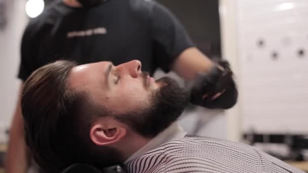 Barber combing beard of client at a barber shop. - Video, Çekim
