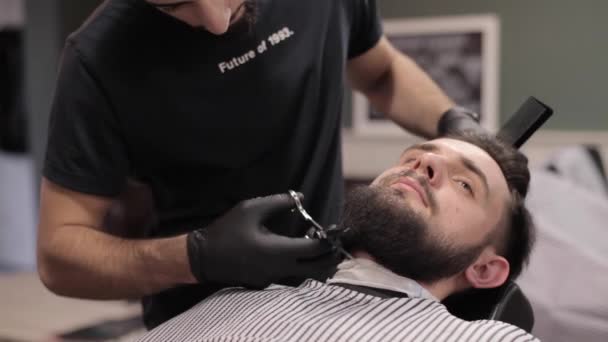 Barber cutting beard with scissors at a barber shop. - Video