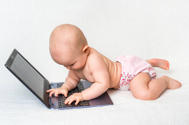 Χαριτωμένο μωρό κορίτσι με μια πάνα παίζοντας με φορητό υπολογιστή  - Φωτογραφία, εικόνα