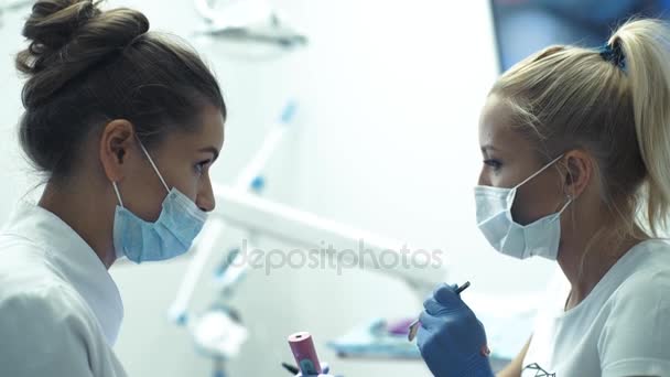 Dentist with assistant examining girls teeth in the dentists chair - Video, Çekim