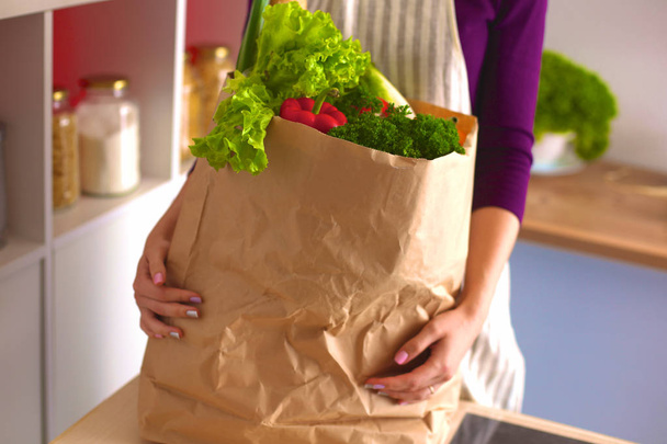 Terveet positiiviset onnellinen nainen tilalla paperi ostoskassi täynnä hedelmiä ja vihanneksia
 - Valokuva, kuva