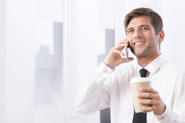 Employee talking on mobile with coffee - Zdjęcie, obraz