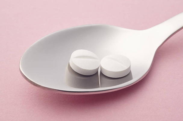 Χάπια και κουτάλι λεπτομέρεια. Ροζ φόντο. Φάρμακο θεραπεία. H - Φωτογραφία, εικόνα