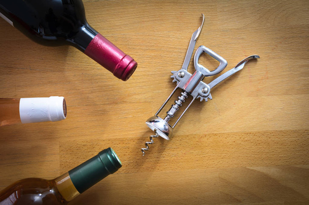 Ahşap masa üzerinde bir tirbuşon ile şarap şişeleri - Fotoğraf, Görsel