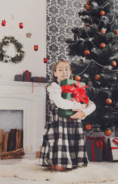 Hermosa niña y regalo de Navidad en el interior
 - Foto, imagen