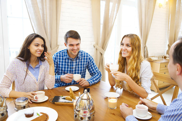 Gruppe von vier glücklichen Freunden treffen sich und reden und essen desse - Foto, Bild