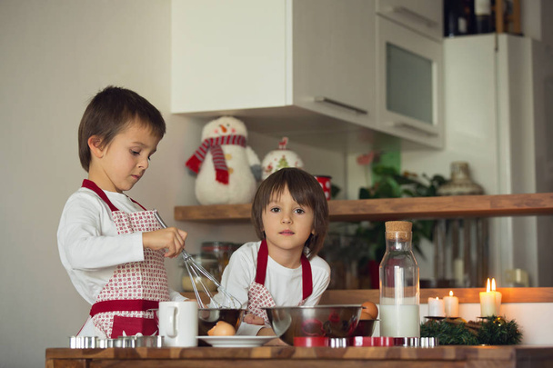 Two sweet children, boy brothers, preparing gingerbread cookies  - 写真・画像