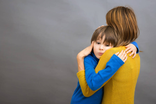 trauriges kleines Kind, Junge, umarmt seine Mutter zu Hause, isoliert imag - Foto, Bild