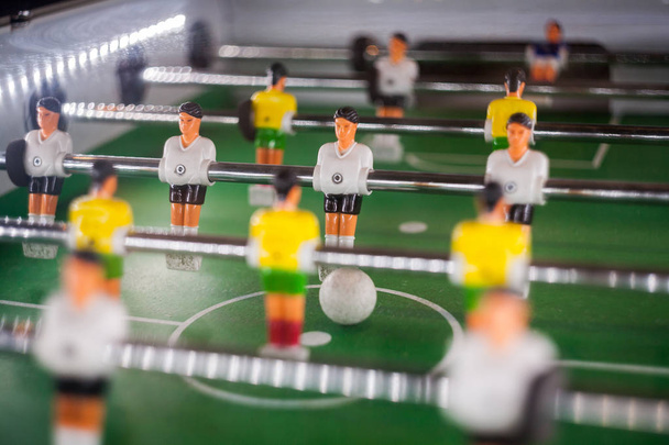 tafel voetbal spel, abstracte licht. Voetbal tafel met Close up van gele en witte spelers. Tafel voetbal voetbalspel (kicker) - Foto, afbeelding