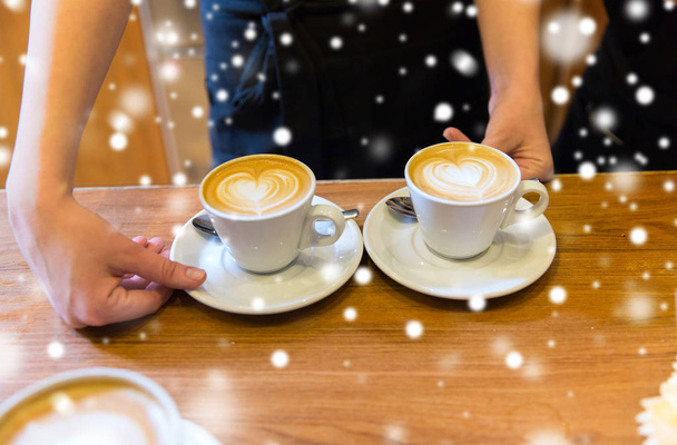 close up of hands with latte art in coffee cup - Φωτογραφία, εικόνα